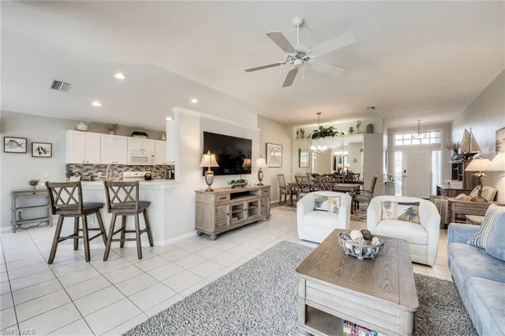 Tiled living room with ceiling fan with notable chandelier