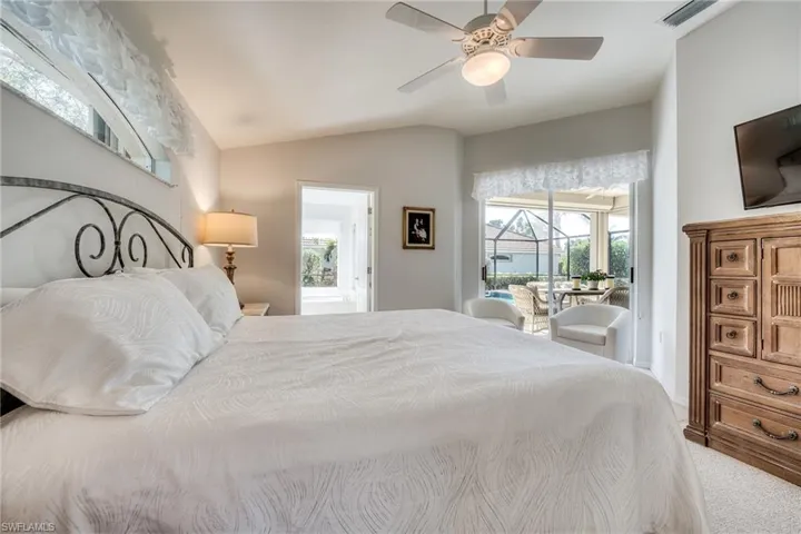 Bedroom featuring vaulted ceiling, access to outside, ensuite bathroom, and ceiling fan