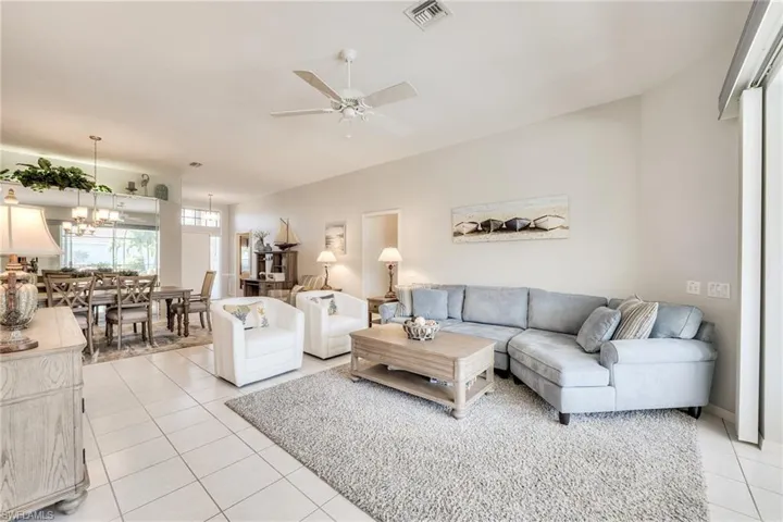 Tiled living room featuring ceiling fan with notable chandelier