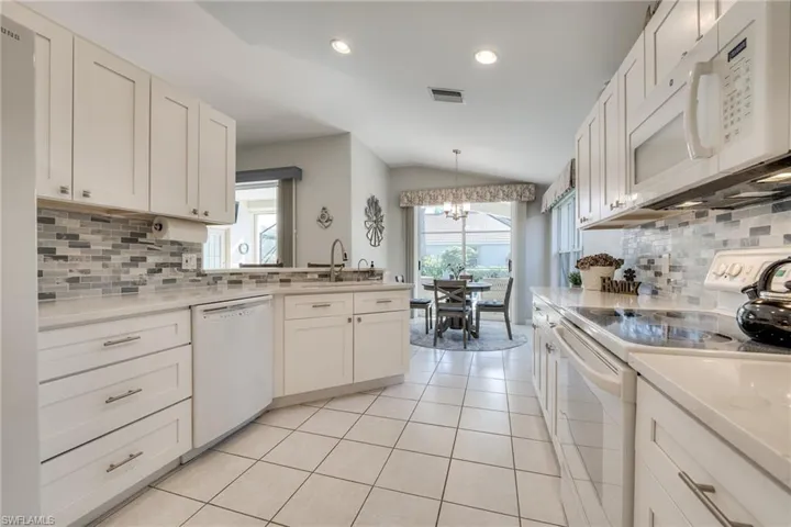 Kitchen featuring white cabinetry, light tile patterned floors, and white appliances