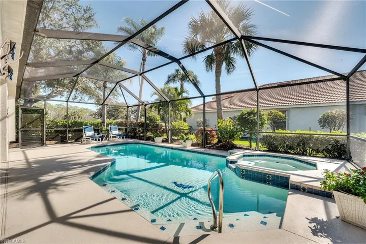 View of swimming pool featuring an in ground hot tub, glass enclosure, and a patio area