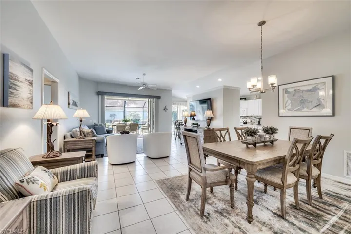 Dining space featuring ceiling fan with notable chandelier and light tile patterned floors