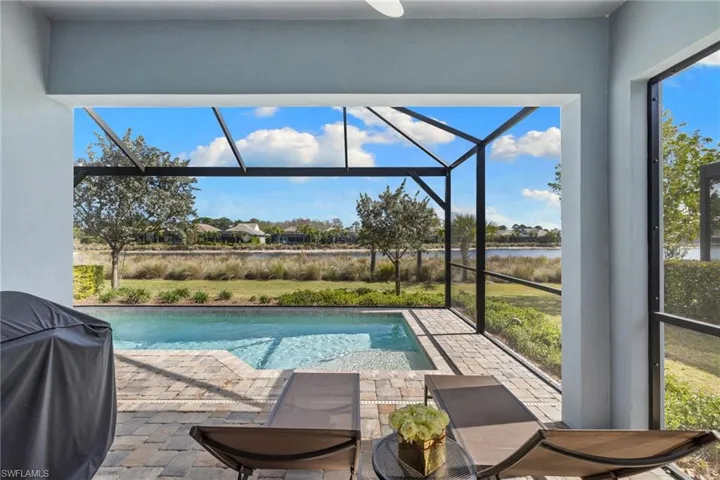 Outdoor pool with grilling area, a sunroom, a lanai, a residential view, and a water view