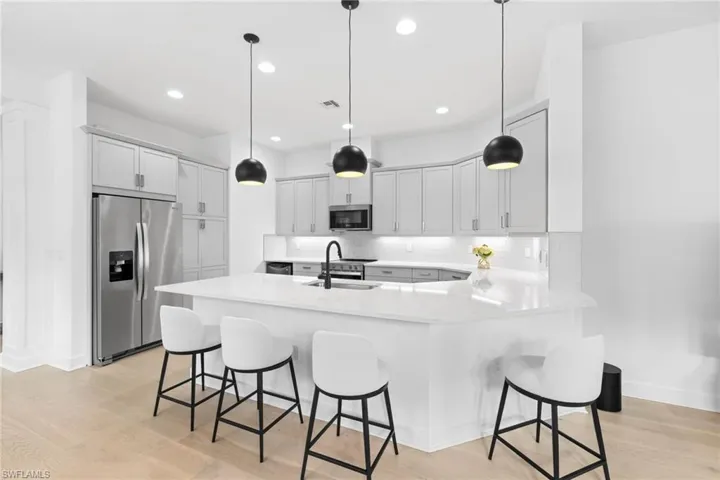 Kitchen with a peninsula, a breakfast bar, stainless steel appliances, backsplash, and light wood-type flooring