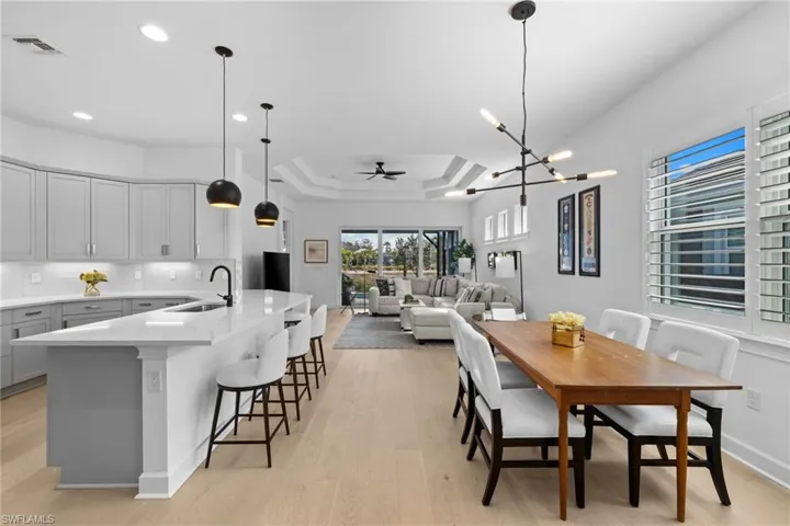 Dining space with a ceiling fan, a tray ceiling, light wood-type flooring, and hanging lights