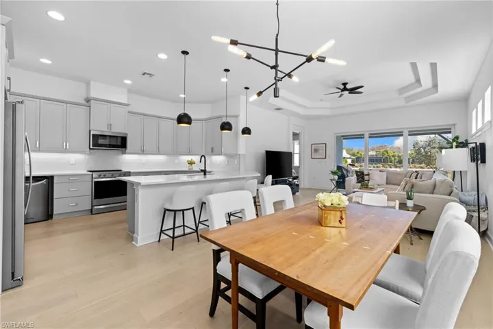 Dining area featuring a chandelier, light wood-style flooring, a tray ceiling, and ceiling fan