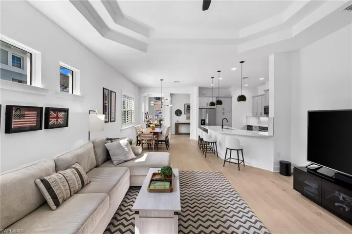 Living room with light wood-style flooring, recessed lighting, a ceiling fan, and a tray ceiling