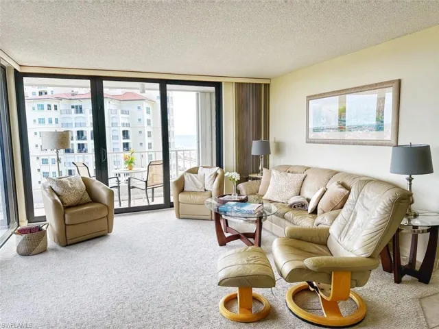 Carpeted living area featuring expansive windows and a textured ceiling