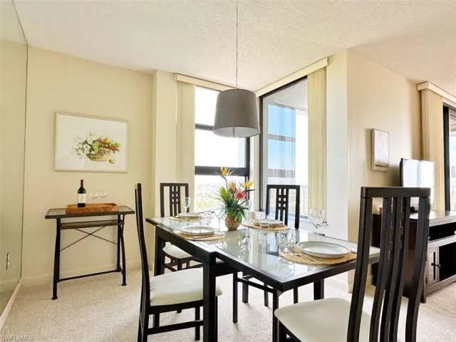 Dining space featuring light colored carpet and a textured ceiling