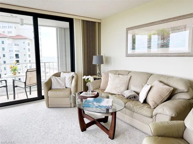 Living area featuring light colored carpet, expansive windows, and a textured ceiling