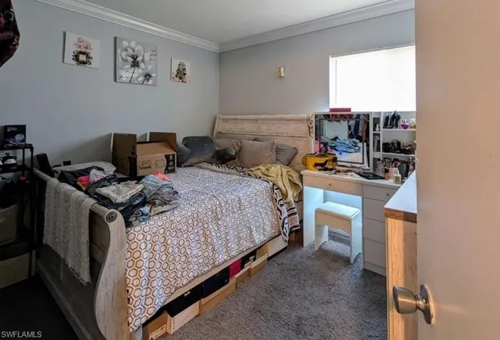 Bedroom with crown molding and dark carpet