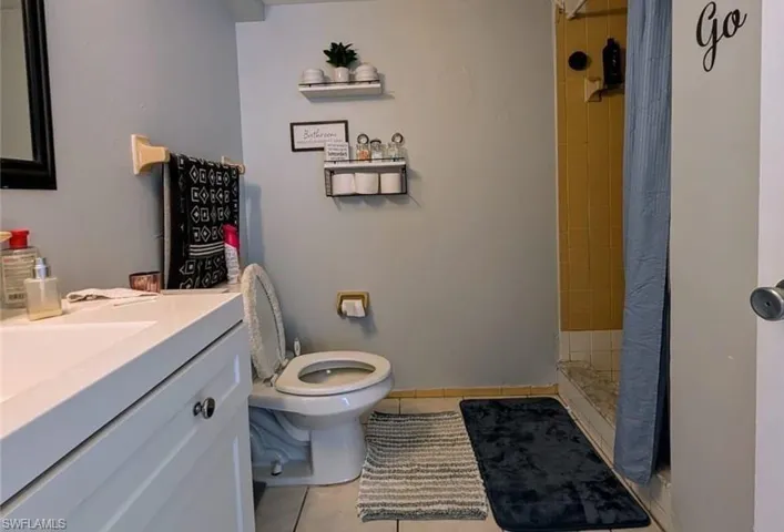 Bathroom featuring toilet, vanity, tile patterned floors, and a shower with curtain