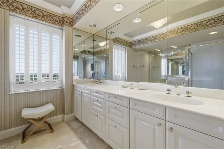 Full bath with double vanity, plenty of natural light, ornamental molding, a shower stall, and light tile patterned flooring
