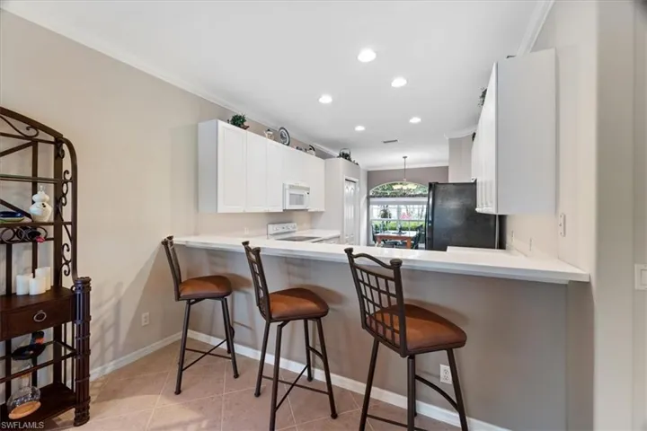 Kitchen featuring light tile patterned floors, recessed lighting, white appliances, and ornamental molding