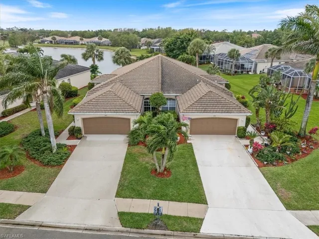 View of front of house featuring a tile roof, driveway, a front yard, and a water view