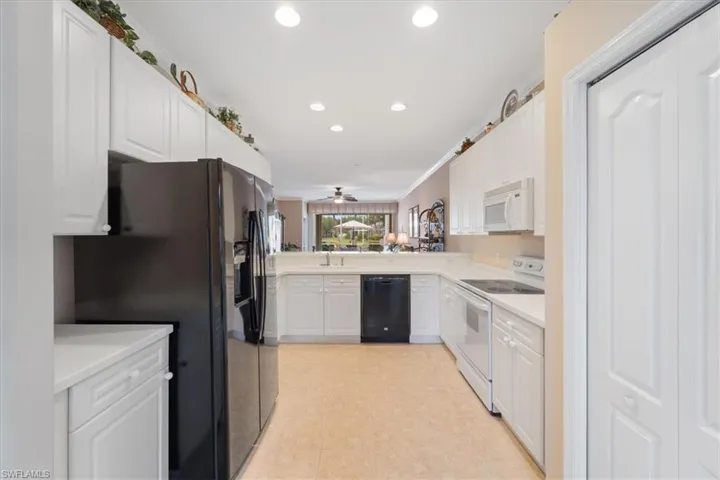 Kitchen featuring recessed lighting, a sink, black appliances, white cabinets, and light countertops