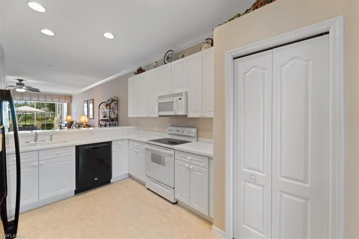 Kitchen with ornamental molding, a sink, white cabinetry, white appliances, and light countertops