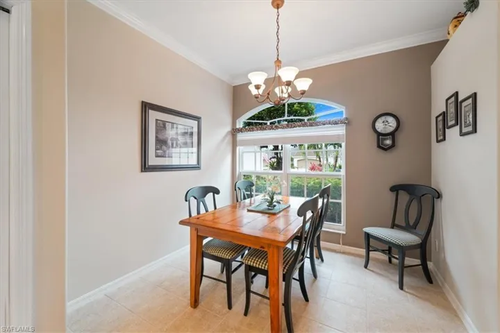 Dining area with light tile patterned floors, baseboards, a notable chandelier, and ornamental molding