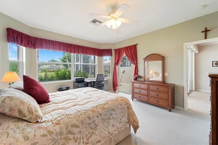 Bedroom featuring multiple windows, visible vents, carpet floors, and ceiling fan
