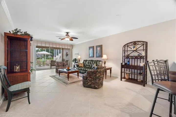 Living area featuring light tile patterned floors, baseboards, ornamental molding, and ceiling fan