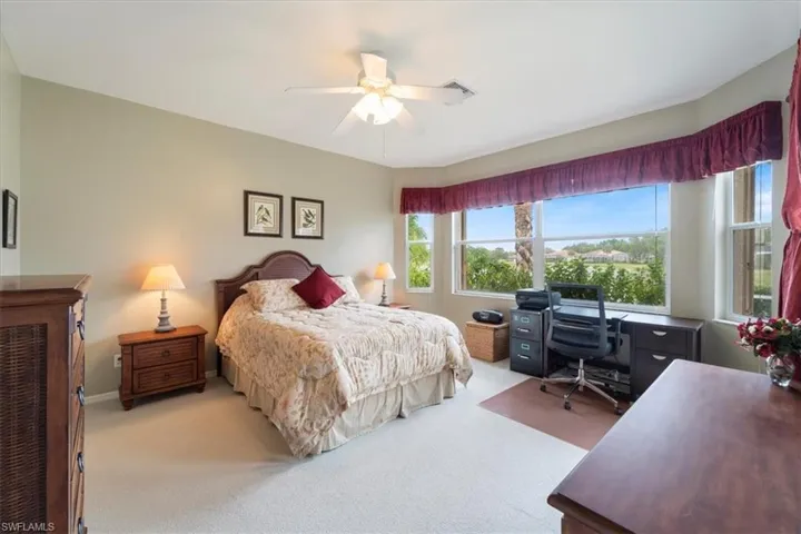 Bedroom with baseboards, light colored carpet, visible vents, and ceiling fan
