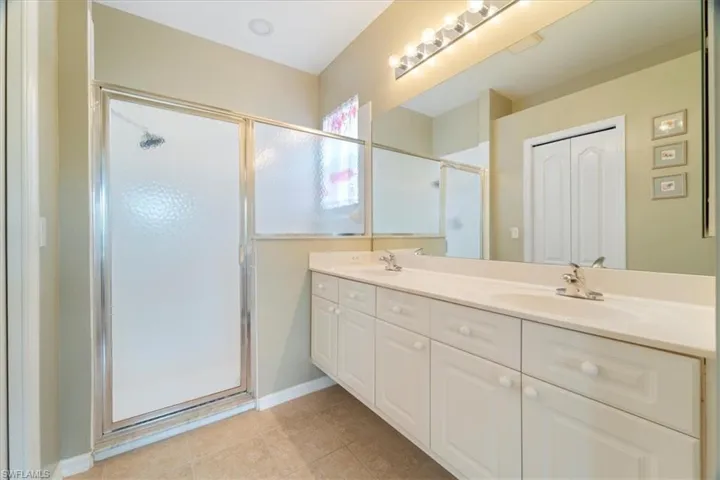 Full bathroom with a sink, a stall shower, double vanity, and tile patterned floors