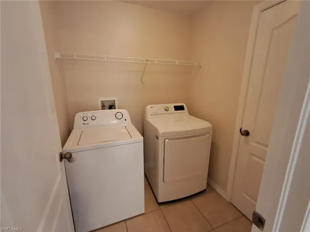 Laundry area with light tile patterned floors and washer and clothes dryer