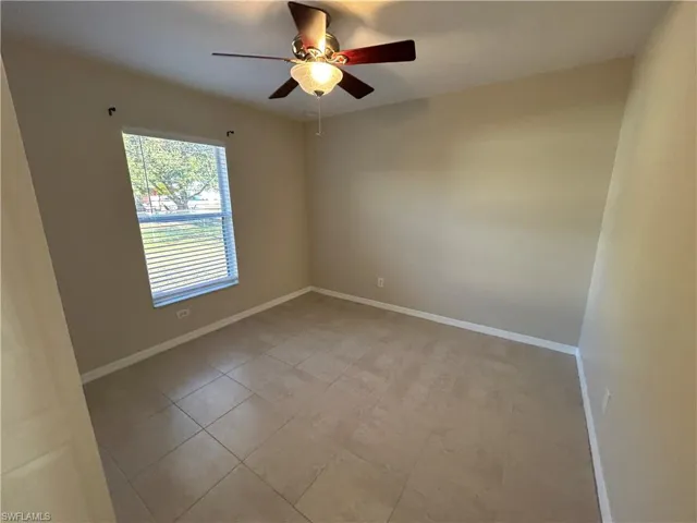 Unfurnished room with ceiling fan and light tile patterned flooring