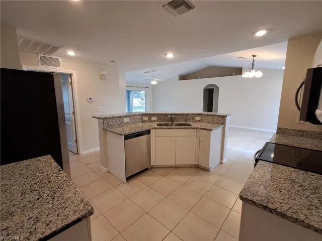 Kitchen with a ceiling fan, stainless steel appliances, light tile patterned floors, vaulted ceiling, and arched walkways
