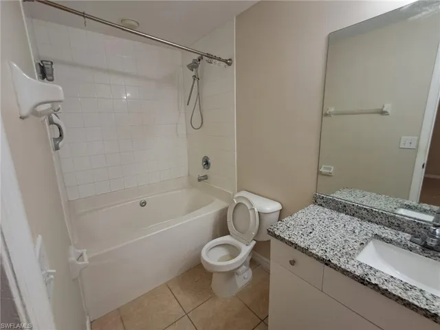 Full bathroom with vanity, light tile patterned floors, and shower / washtub combination