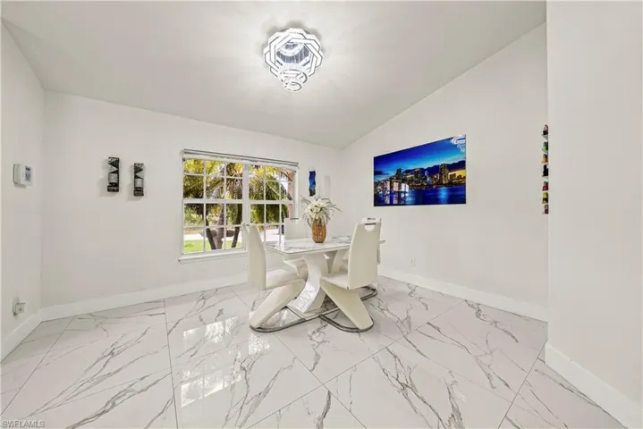 Dining area with lofted ceiling and light marble finish floors