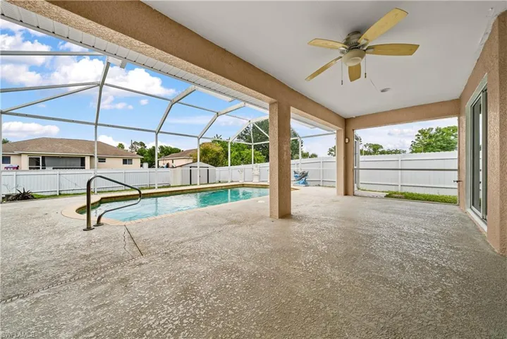 View of pool featuring patio surround, a sunroom, glass enclosure, and a fenced backyard