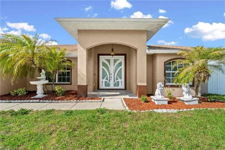 View of exterior entry featuring stucco siding and a yard