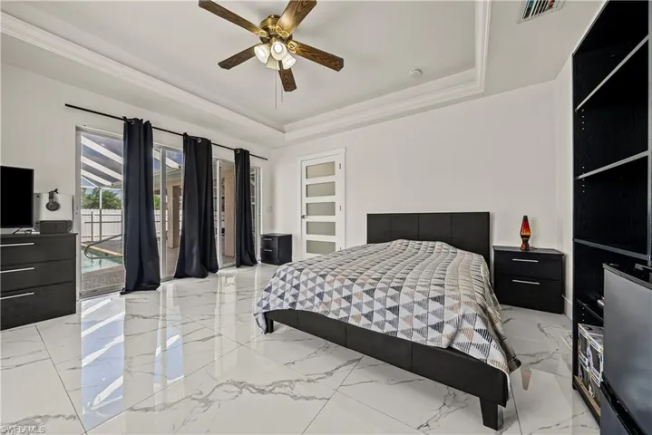Bedroom featuring access to exterior, a ceiling fan, and a raised ceiling