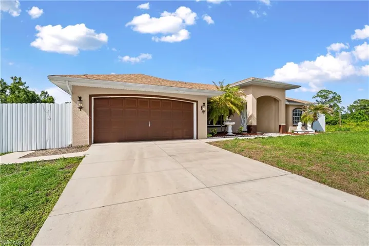 View of front of home featuring stucco siding, a front lawn, a garage, and concrete driveway