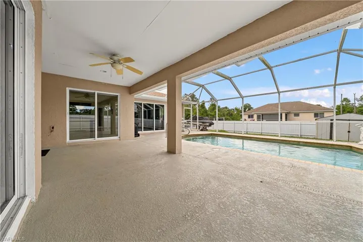 View of swimming pool with patio surround, a sunroom, a lanai, and a shed
