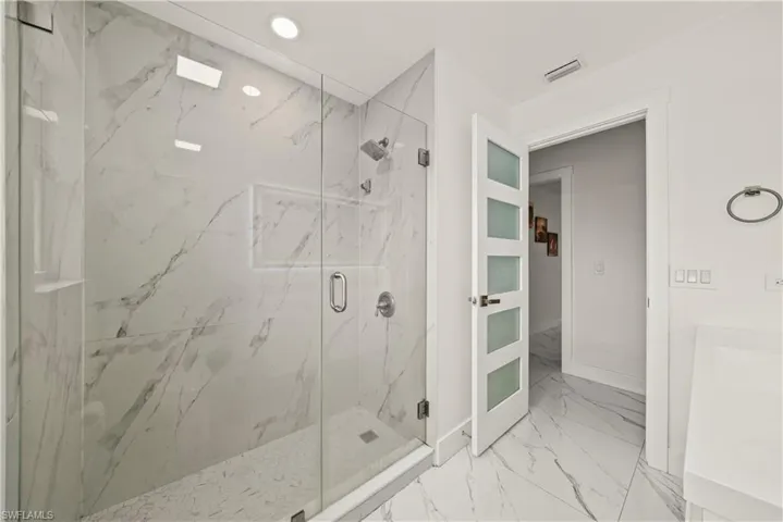 Bathroom with a marble finish shower, vanity, light marble finish flooring, and recessed lighting