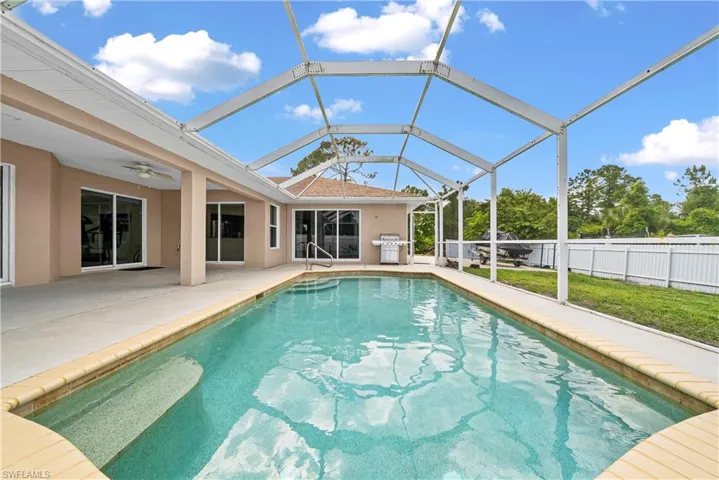 View of swimming pool featuring a sunroom, a grill, a lanai, and patio surround