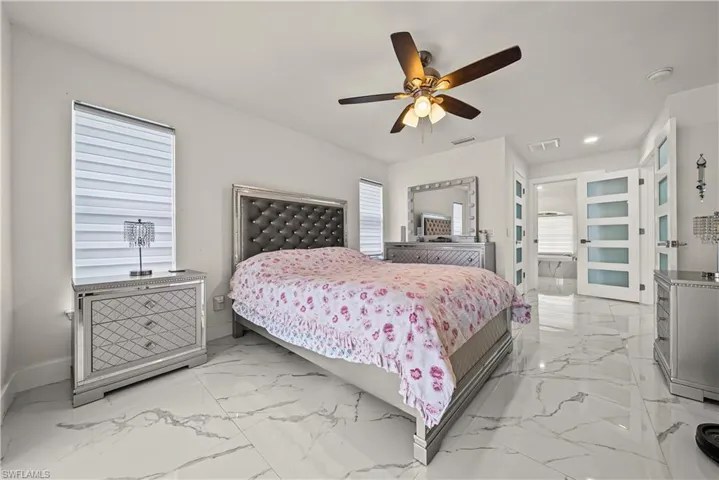 Bedroom featuring a ceiling fan, light marble finish floors, and recessed lighting