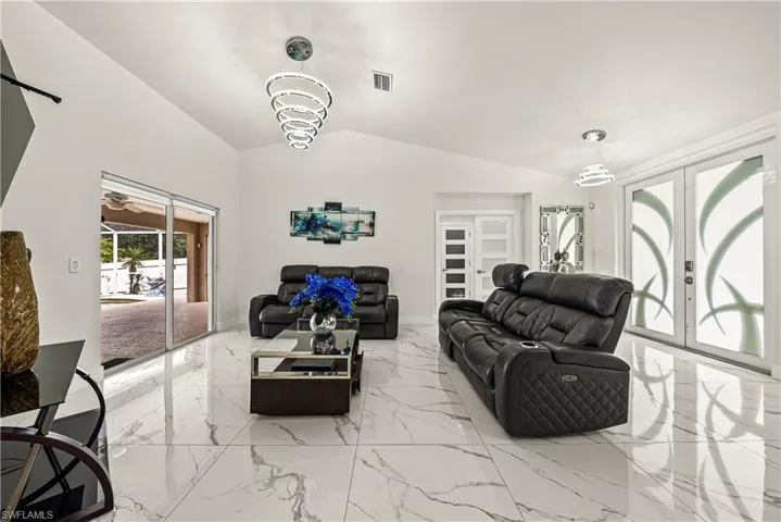 Living area with french doors, lofted ceiling, and light marble finish floors
