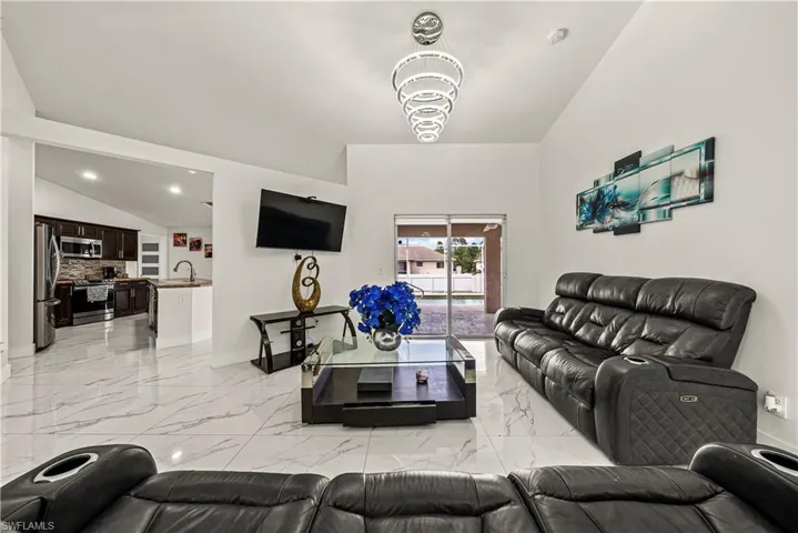 Living area with lofted ceiling, light marble finish flooring, and recessed lighting