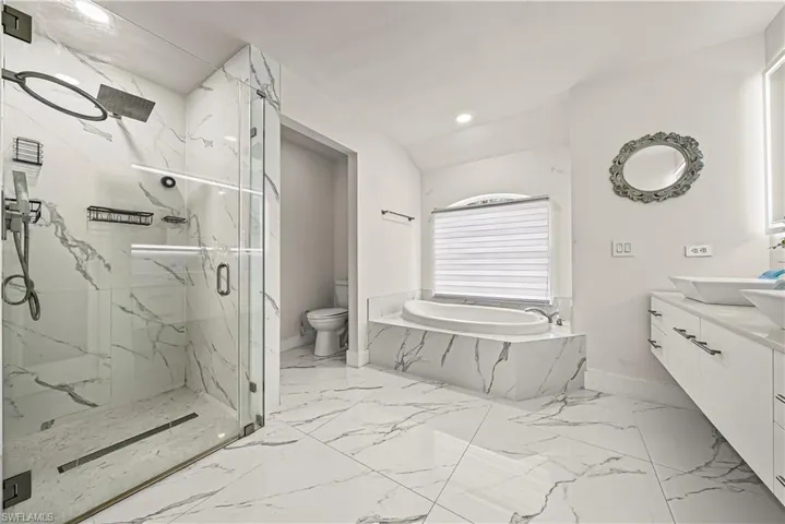 Full bath featuring a marble finish shower, a bath, vanity, light marble finish floors, and recessed lighting