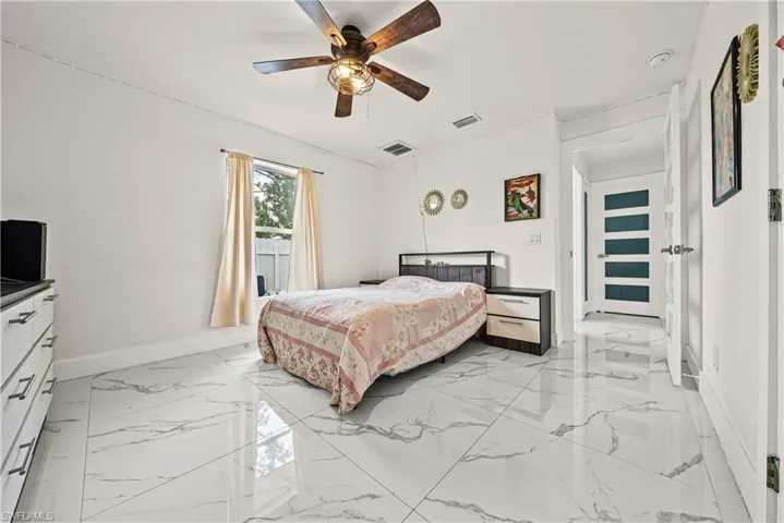 Bedroom with ceiling fan and light marble finish floors