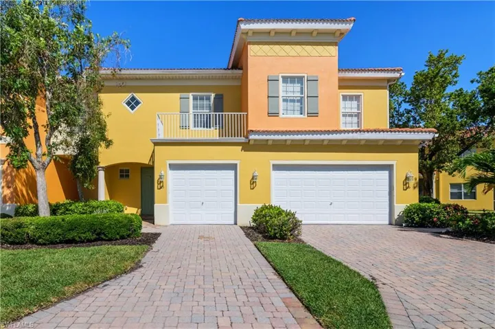 View of front of property featuring a balcony, a tile roof, a garage, stucco siding, and decorative driveway