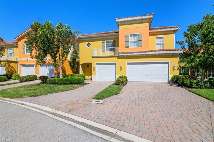 View of property featuring a tiled roof, an attached garage, stucco siding, and decorative driveway