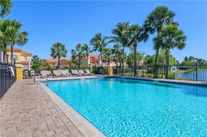 Community pool with a patio area and fence