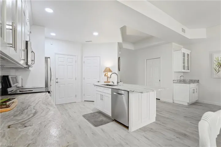 Kitchen with a sink, stainless steel appliances, light wood-type flooring, and white cabinets