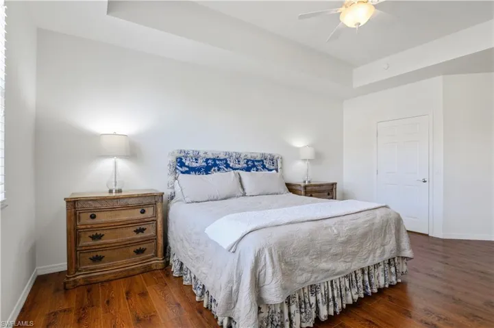 Bedroom with baseboards, a raised ceiling, ceiling fan, and wood finished floors