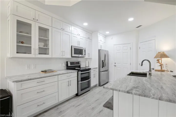 Kitchen featuring a sink, white cabinetry, light wood-type flooring, and appliances with stainless steel finishes