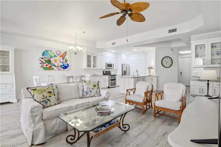 Living area with ceiling fan with notable chandelier, light wood-type flooring, and visible vents